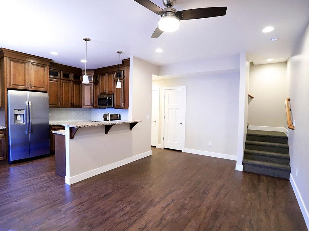 Large Front Room Space With Dark Wood Flooring, Light and Fan Fixture, Near Kitchen and Stairs at Moenave Tonwhomes in Springdale, Utah