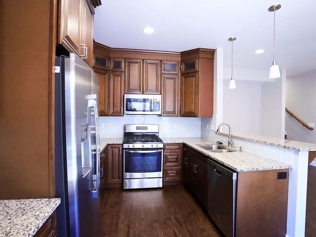 Contemporary Kitchen with Dark Wood Cabinetry, Marble Countertops, and Sleek Appliances at Moenave Townhomes in Springdale, Utah
