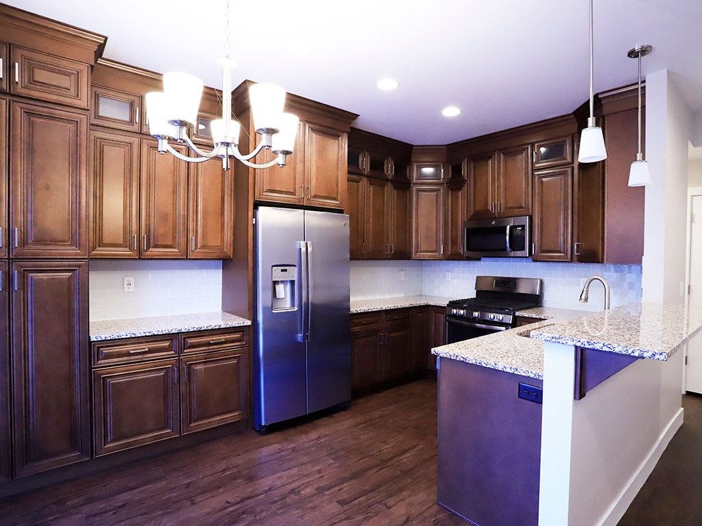 Spacious Kitchen with Dark Wood Cabinetry, Wood Flooring, Light Fixtures, and Marble Countertops at Moenave Townhomes in Springdale, Utah