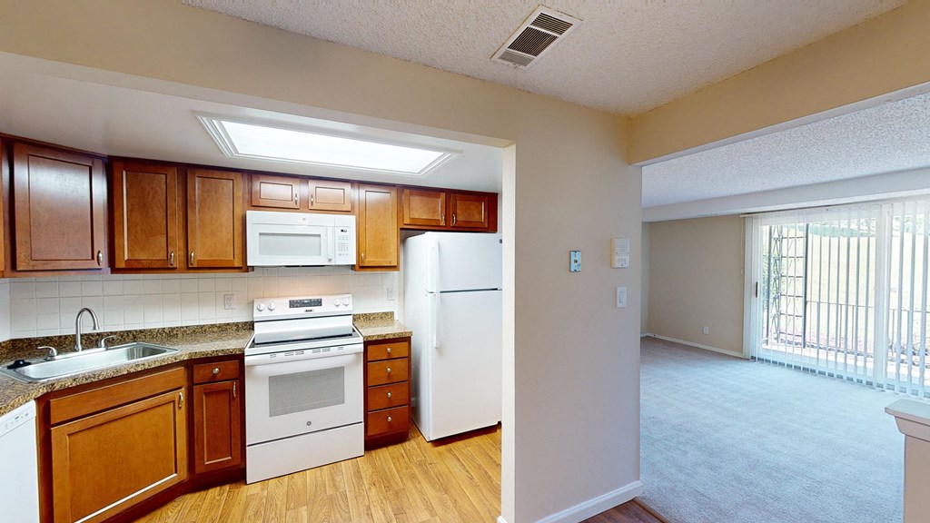 an empty kitchen with white appliances and wooden cabinets