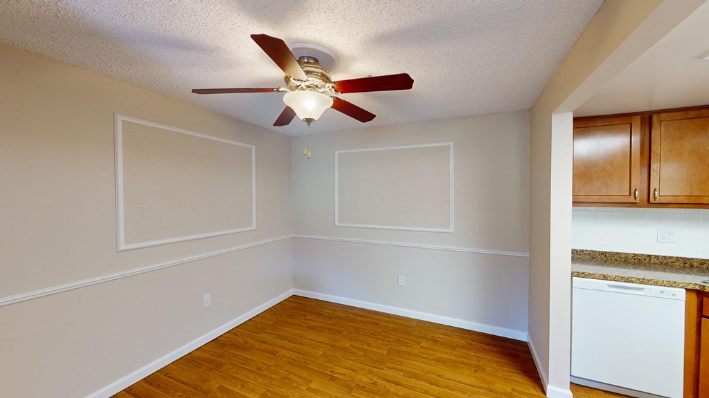an empty room with a ceiling fan and wood floors