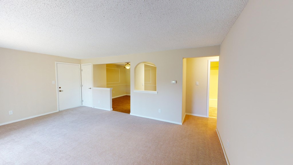 an empty living room and dining room with white walls
