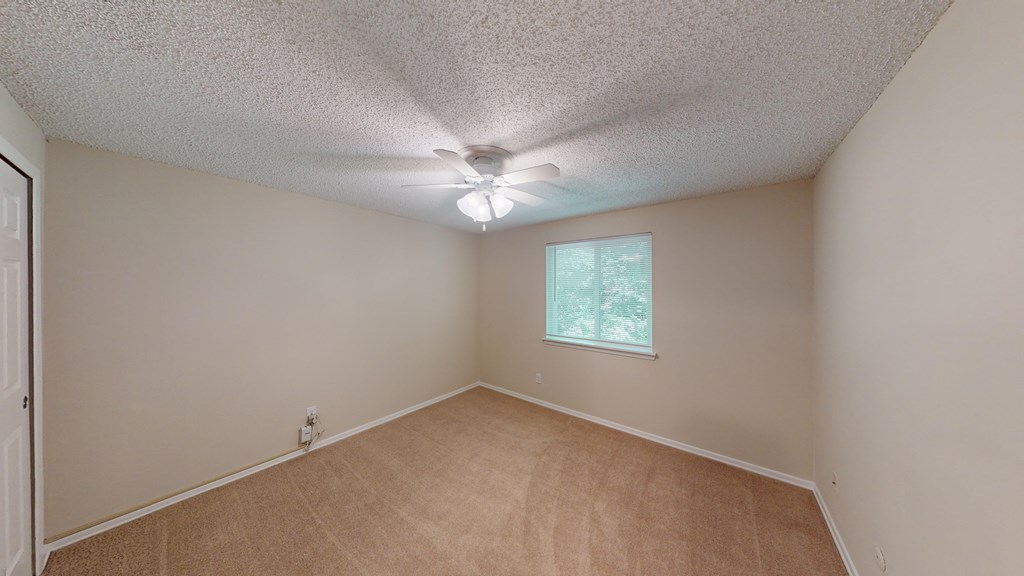 an empty living room with a ceiling fan and a window