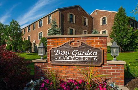 a sign for try garden apartments in front of a brick building