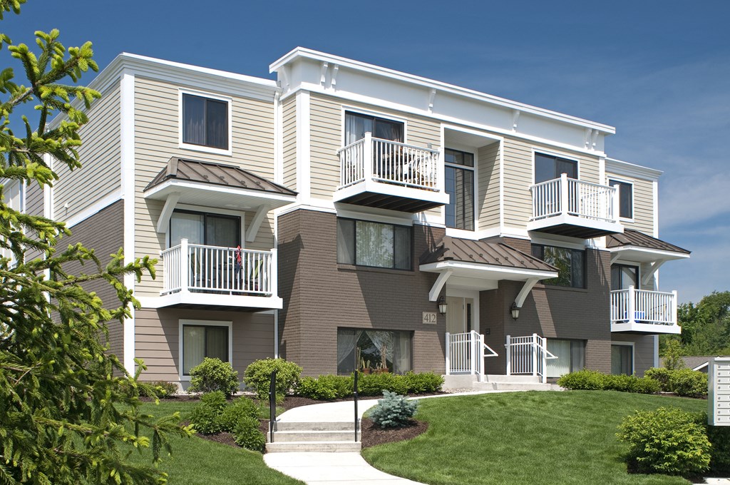 a beige and white apartment building with balconies and a lawn