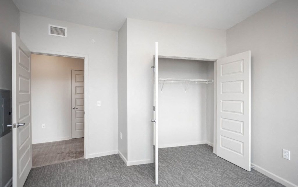 an empty bedroom with a closet and a mirrored closet door