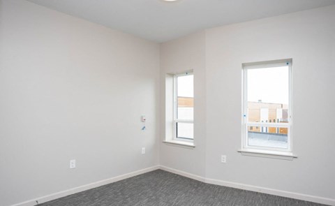 a bedroom with two windows and white walls