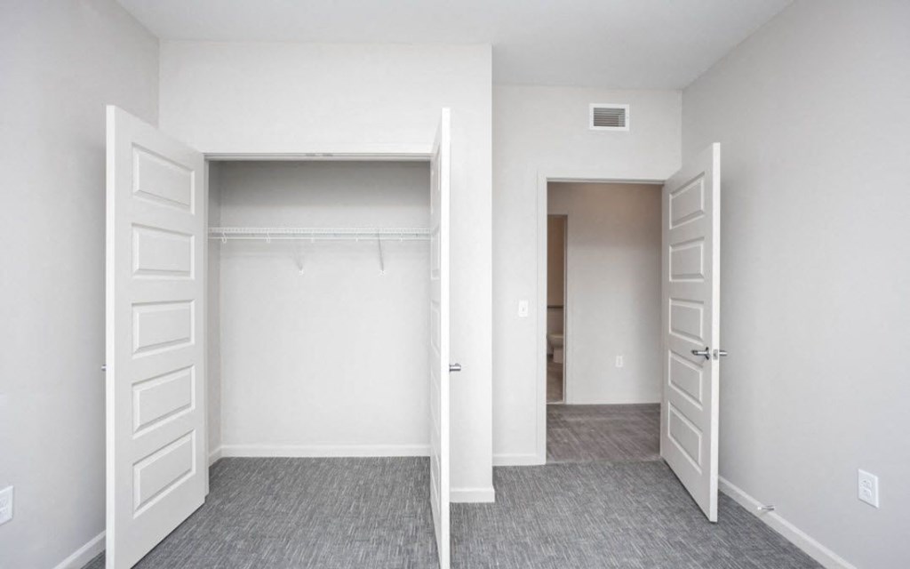 an empty bedroom with white doors and a closet