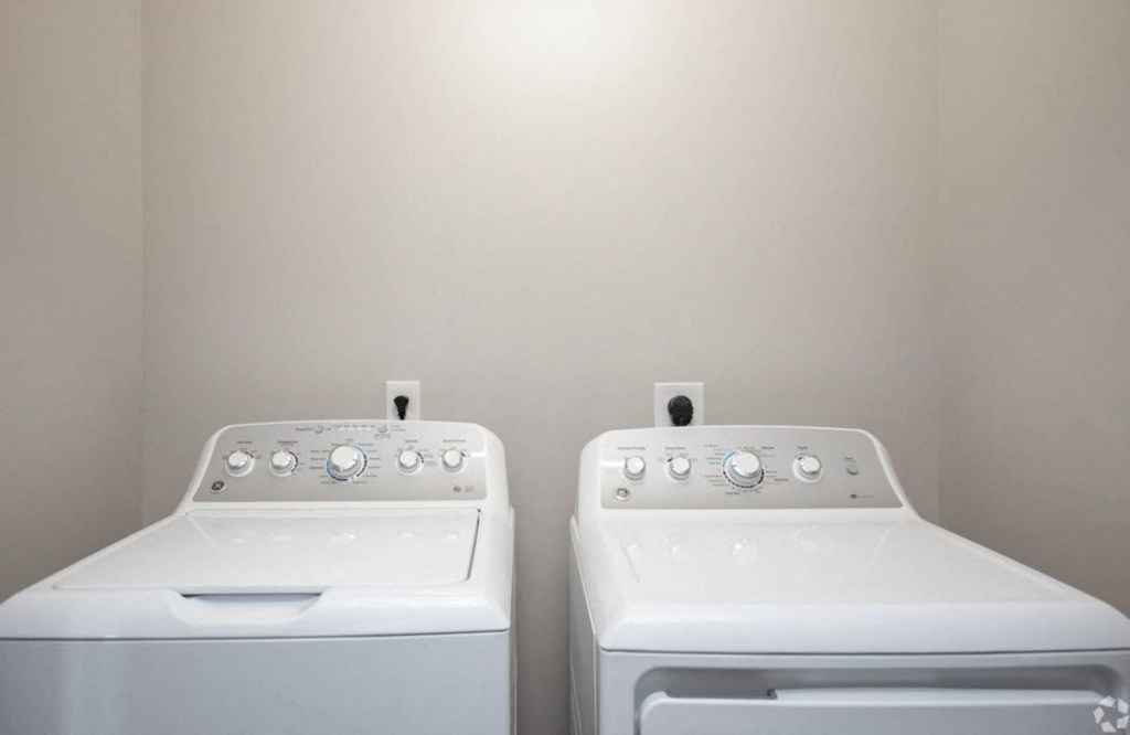 two white washers and dryers in a white laundry room