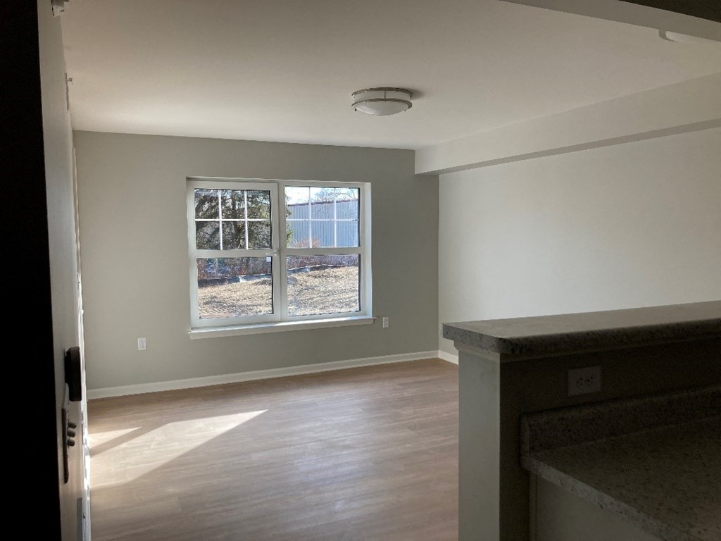 a living room with a large window and wooden floors