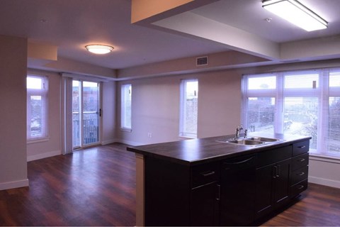 A kitchen with a black counter top and wooden floors.