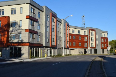 A row of modern apartment buildings are lined up along a street.