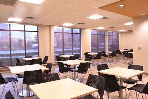 A room with tables and chairs and windows.