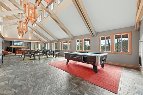 A room with a pool table and a red rug.