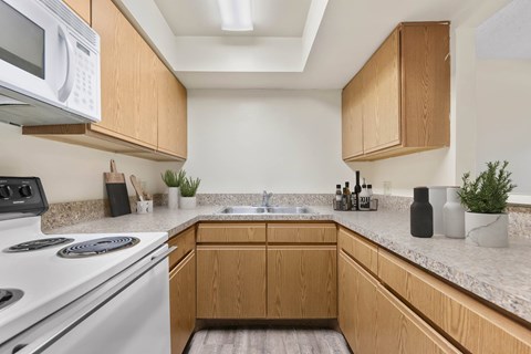 A kitchen with wooden cabinets and a white stove top oven.