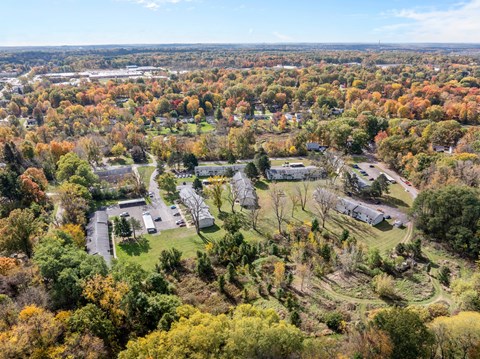 A bird's eye view of a residential area surrounded by trees in autumn.