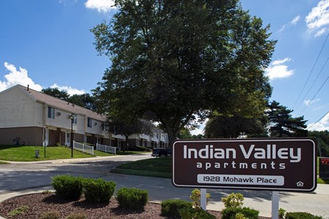 a sign valley apartments in front of a tree