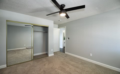 Empty bedroom with mirrored closet and ceiling fan at The Dexter Apartments, Denver, Colorado