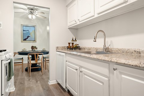 A kitchen with white cabinets and a marble countertop.