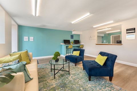 A living room with a blue chair and a glass table.