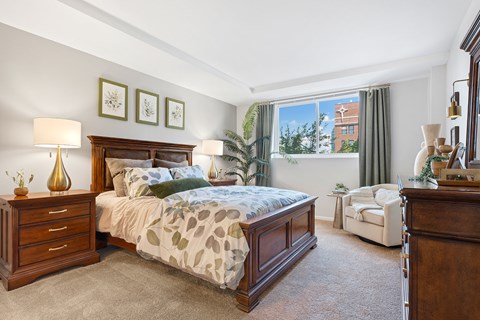 A bedroom with a large bed and a chair.