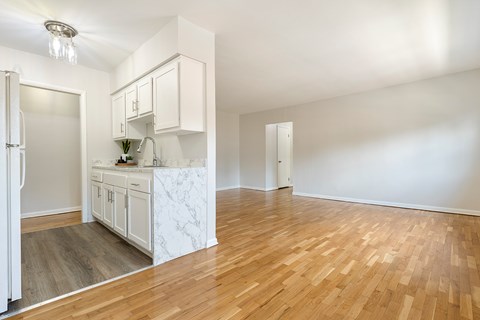 A kitchen with white cabinets and a marble island.