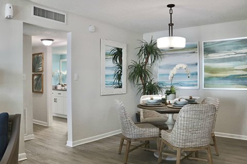 A dining room with a table set for two and a painting on the wall.