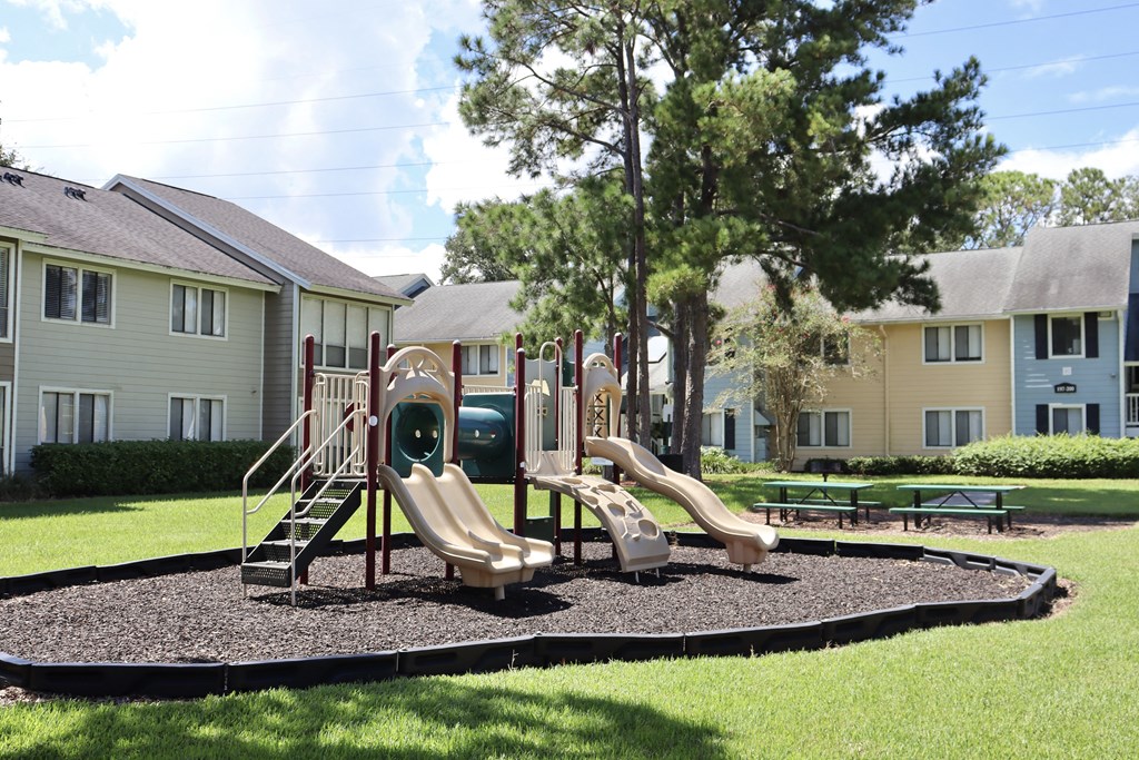 A playground with a slide and a green slide cover.
