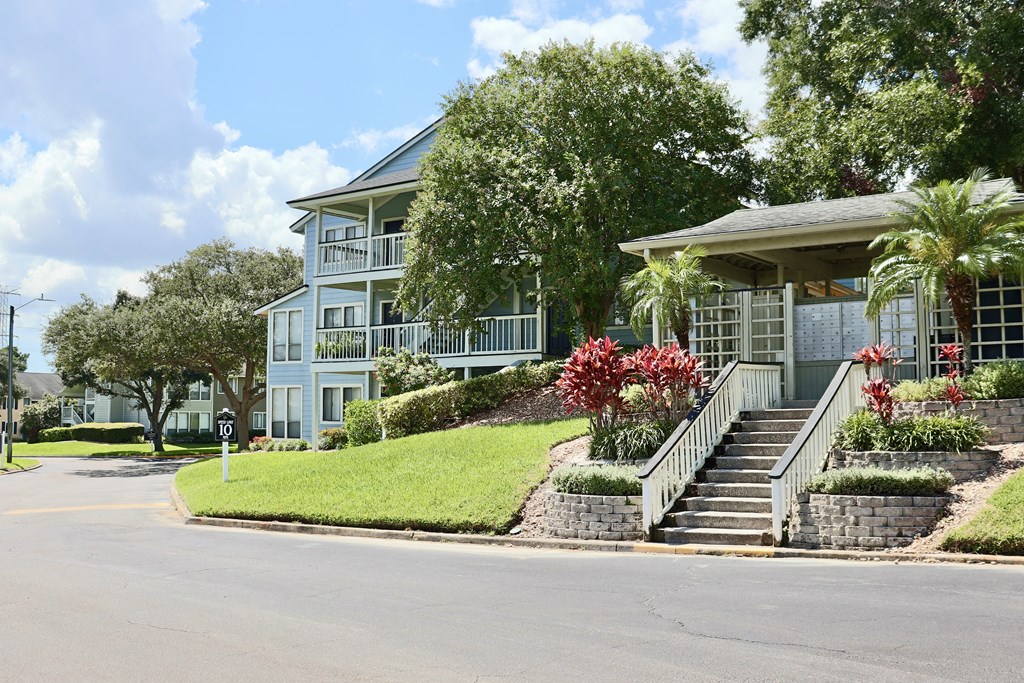 A blue house with a white fence and a red flower bush.