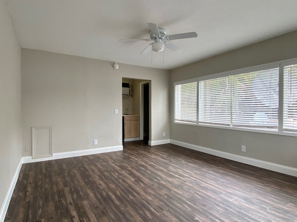an empty living room with a ceiling fan and a large window