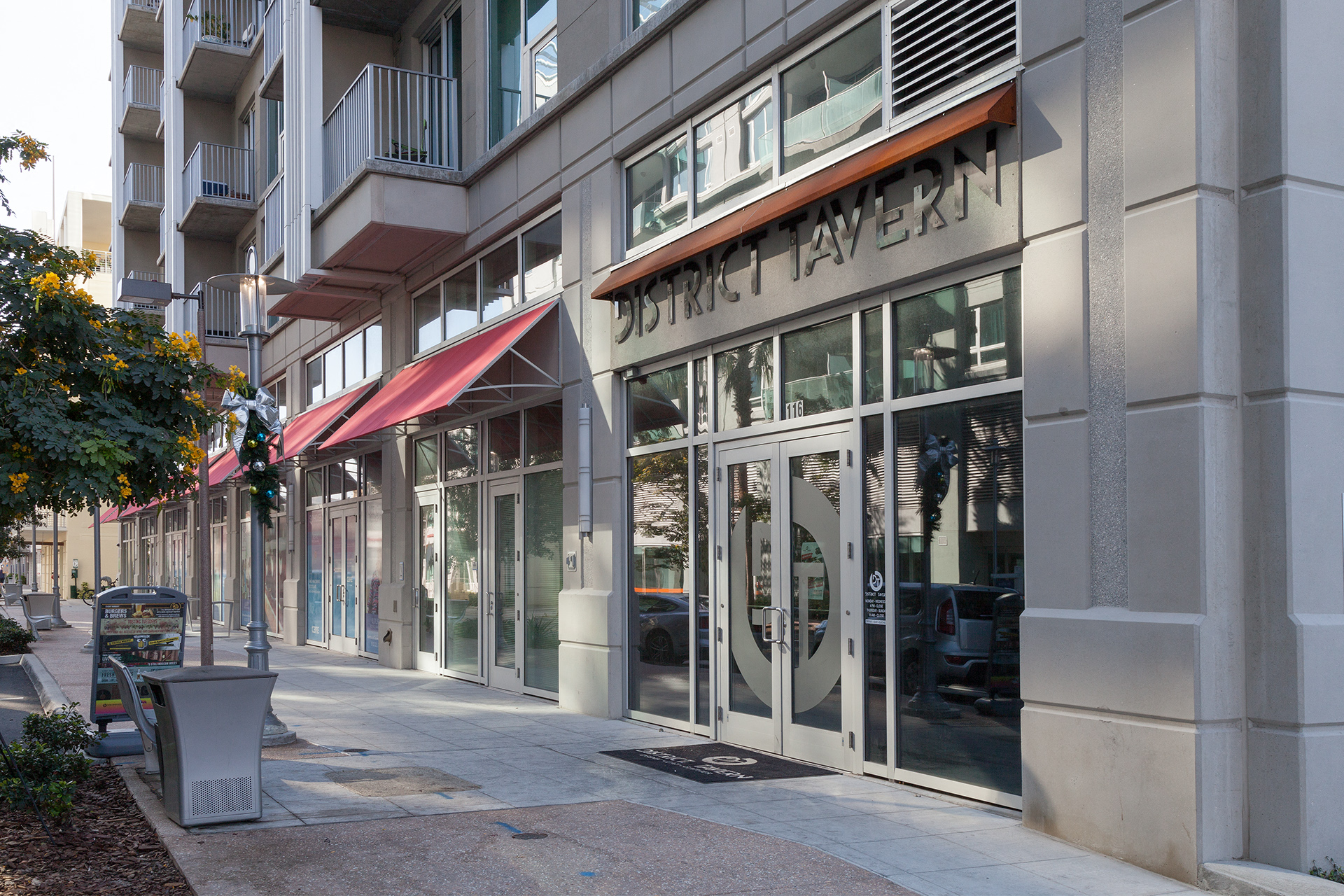 The entrance to a building with a red awning and glass doors.