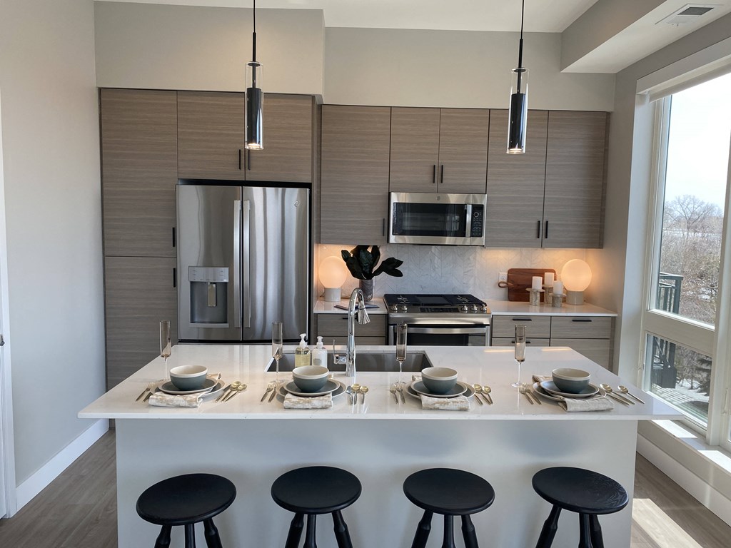a kitchen with a large center island with a white counter top and black stools
