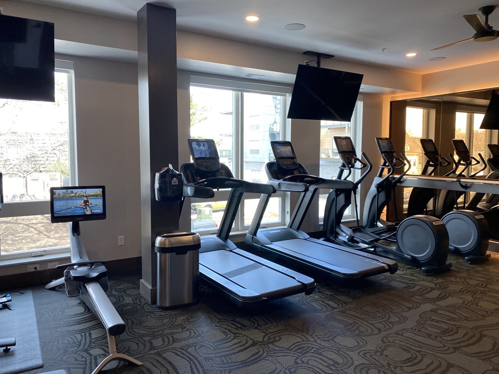 a room filled with lots of cardio equipment and a flat screen tv