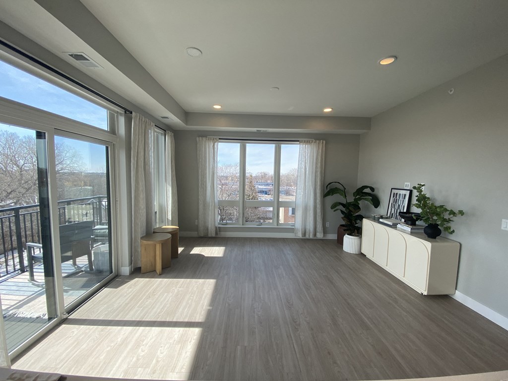 a living room with hardwood floors and a sliding glass door leading to a balcony