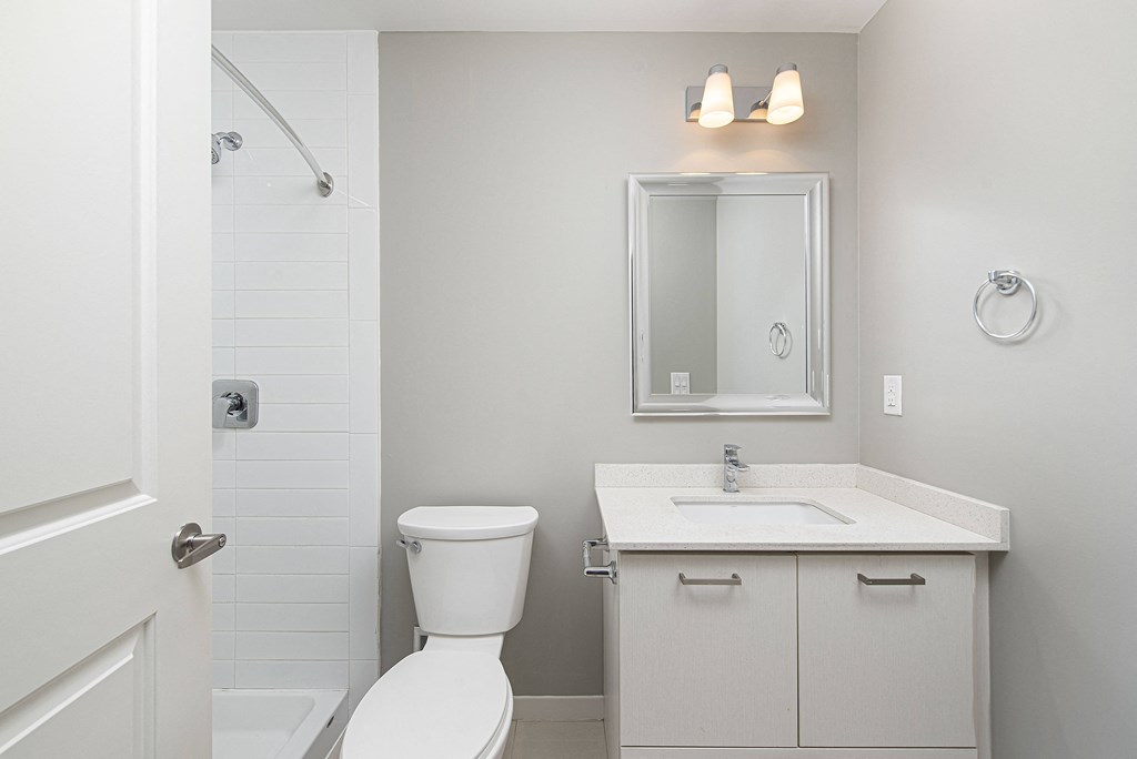 a bathroom with a toilet sink and shower and a mirror