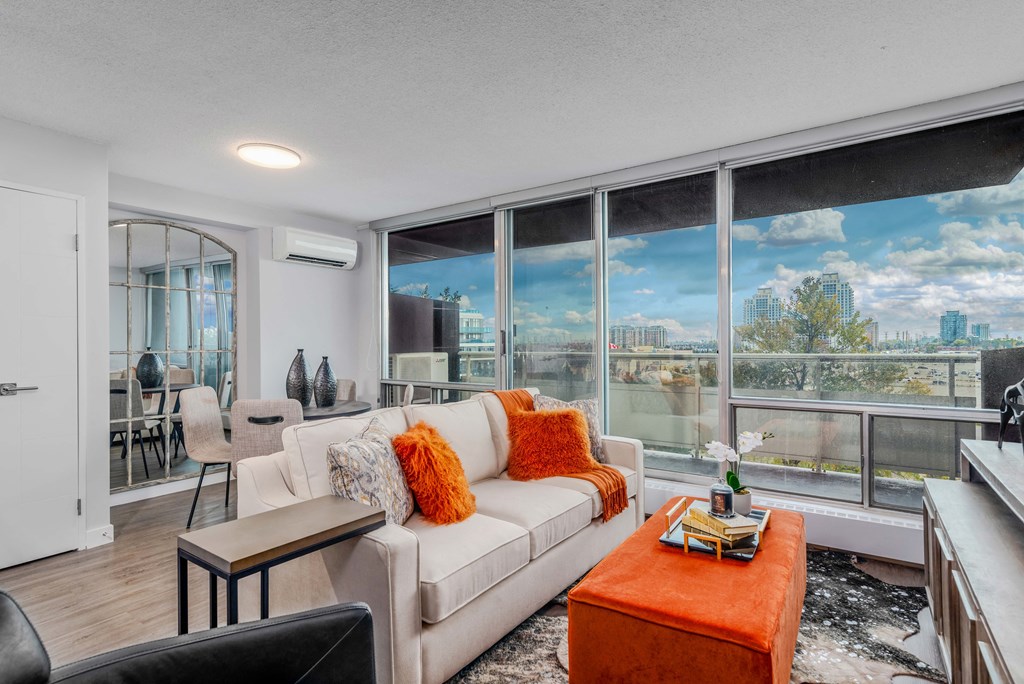 a living room with a white couch and a window with a view of the city