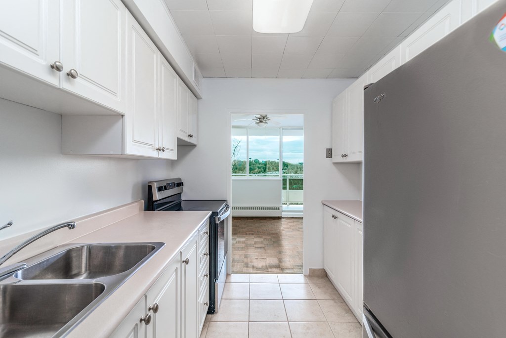 Updated kitchen with white cabinets and stainless steel appliances, open to dining room