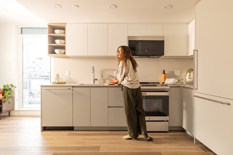 A woman is standing in a modern kitchen.