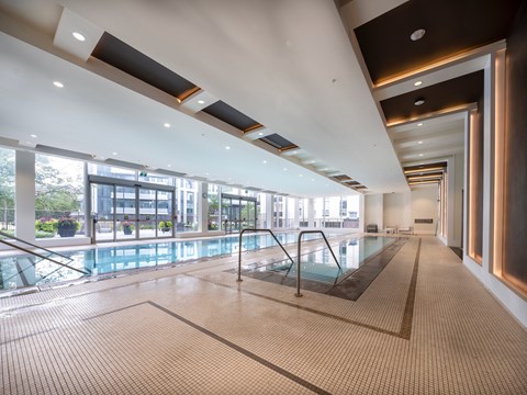 A large indoor swimming pool with a tiled floor and a glass divider.