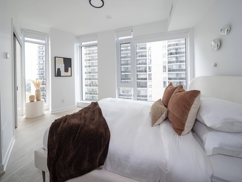 A bedroom with a large bed and a view of a building outside the window.