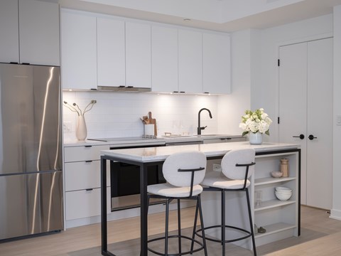 A modern kitchen with white cabinets and a stainless steel refrigerator.