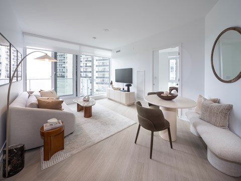 A modern living room with a white sofa, a brown chair, and a white coffee table.