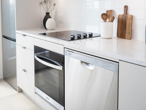 A modern kitchen with a stainless steel oven and white countertop.
