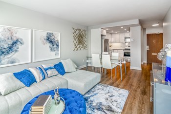 Open concept living and dining room staged with furniture. The kitchen is open from the dining room. - Photo Gallery 3