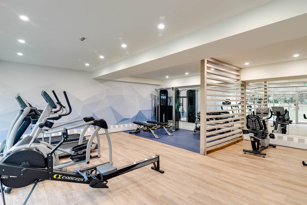 a gym with various machines and weights on a wooden floor