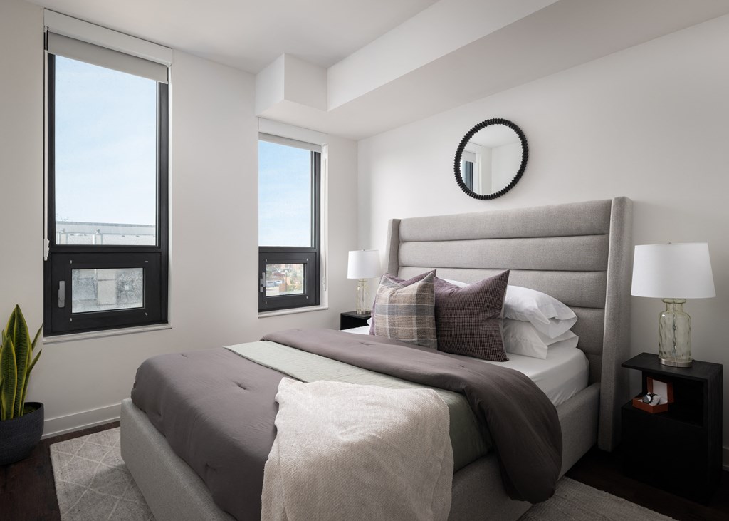 a bedroom with a large bed and two windows