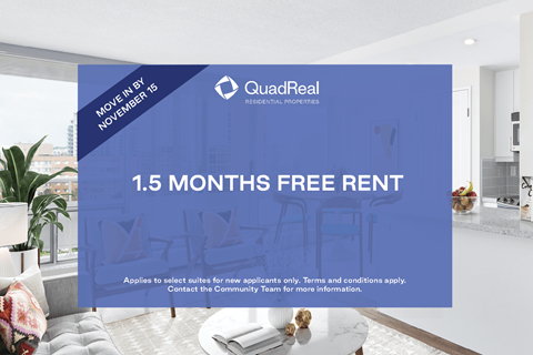 A room with a sofa and a coffee table with a QuadReal advertisement on the wall.