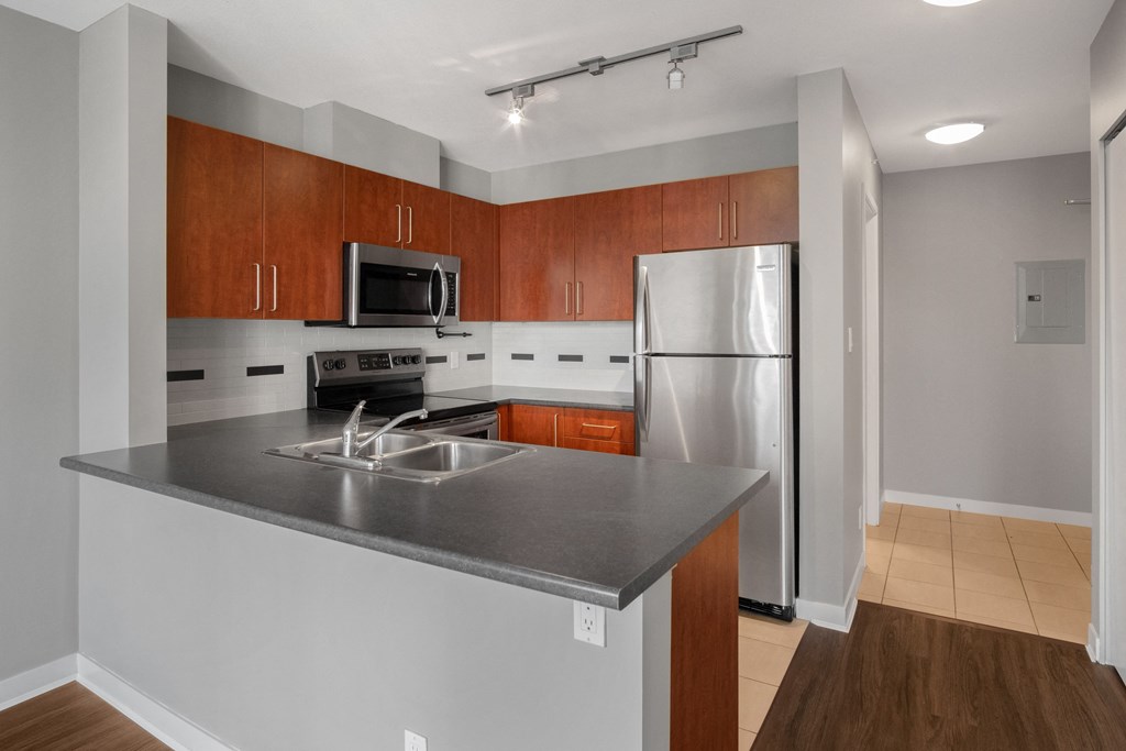 an empty kitchen with stainless steel appliances and wooden cabinets