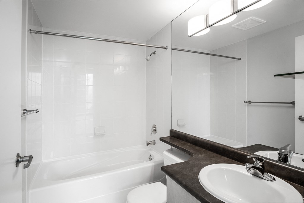 Image of the bathroom in suite 2308, which includes stone countertops, stunning white tile, and chrome fixtures.