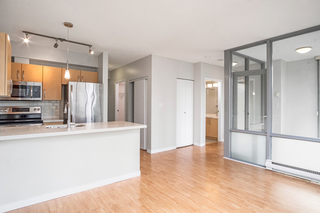 View from the living room of 408, looking back at the kitchen. In sight is the kitchen, and doors to other rooms.